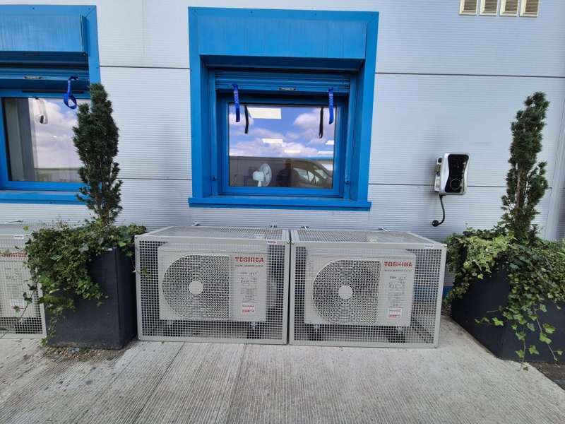 Outdoor air conditioning condenser units installed in protective mesh security cages